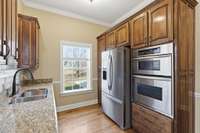 Upscale kitchen showcasing a large granite-topped island with Jenn‑Air cooktop, rich custom cabinetry, built‑in wine storage, and generous counter space, all opening to a cozy breakfast nook perfect for casual dining.