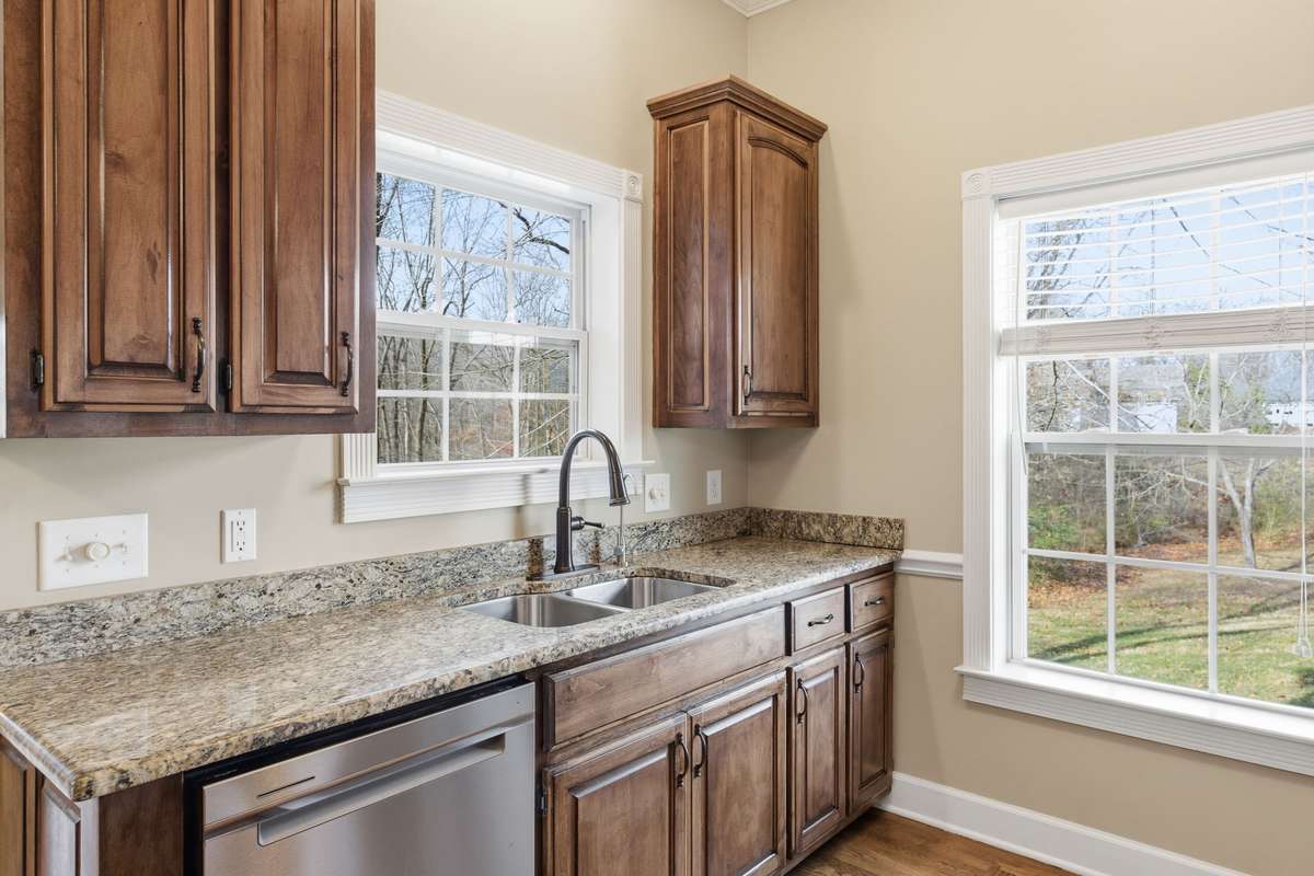 Upscale kitchen showcasing a large granite-topped island with Jenn‑Air cooktop, rich custom cabinetry, built‑in wine storage, and generous counter space, all opening to a cozy breakfast nook perfect for casual dining.