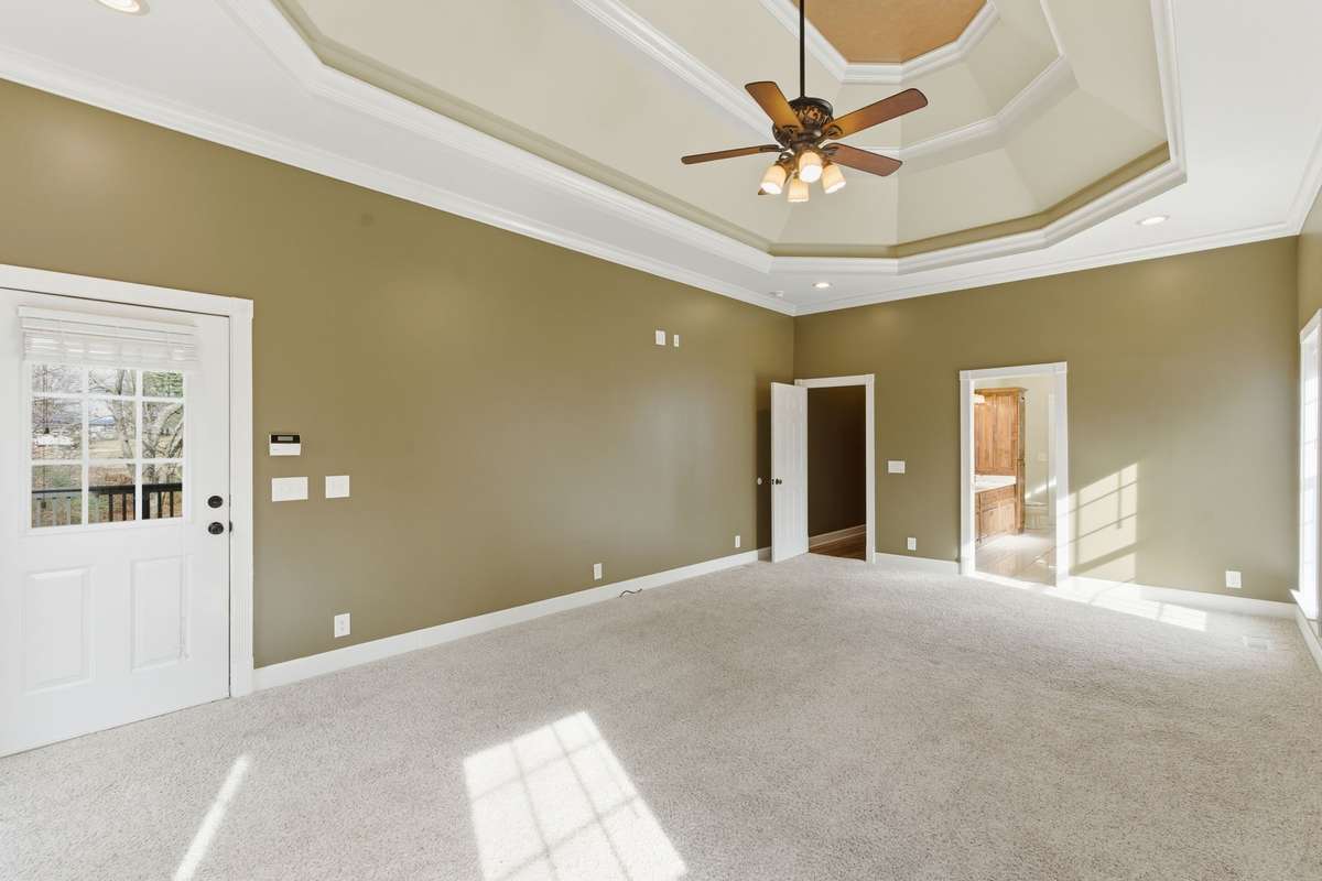 Spacious primary suite with a dramatic double-tray ceiling, cozy fireplace, and wall of windows that fill the room with natural light and peaceful views, creating a serene retreat to begin and end each day. Private entrance to covered deck!