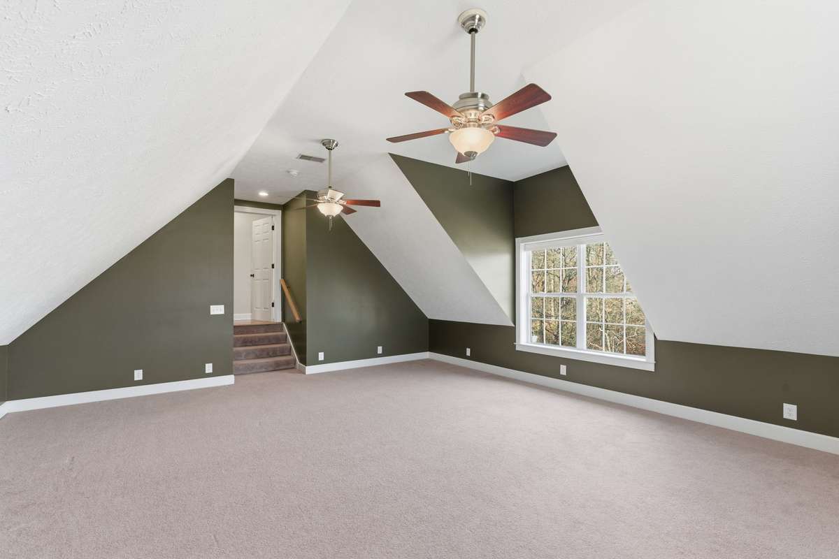 Expansive bonus room over the garage with unique architectural angles, dual ceiling fans, and large windows that bring in plenty of natural light—perfect for a media room, playroom, home gym, or additional living space.