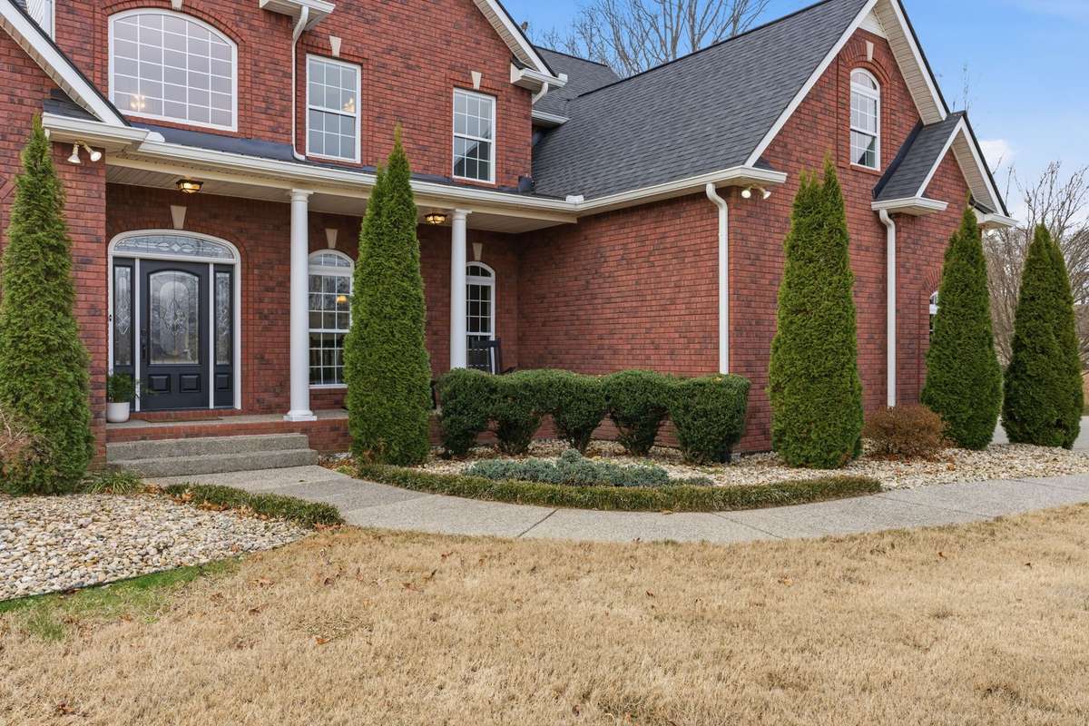 Charming covered front porch with classic columns, decorative glass double doors, and room for rocking chairs, creating a warm Southern welcome the moment you arrive.