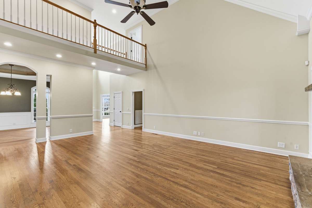 Main floor family/living room features a stacked-stone fireplace, soaring vaulted ceilings, and hardwood floors, with easy walkout access to the covered deck that is perfect for grilling, relaxing, and entertaining.