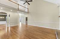 Main floor family/living room features a stacked-stone fireplace, soaring vaulted ceilings, and hardwood floors, with easy walkout access to the covered deck that is perfect for grilling, relaxing, and entertaining.