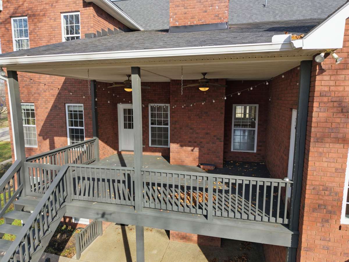 All-brick estate exterior showcasing classic architecture, upper and lower covered patios, and a custom staircase leading to the walkout basement, all set on a spacious corner lot in Portland’s prestigious Dogwood Springs neighborhood.