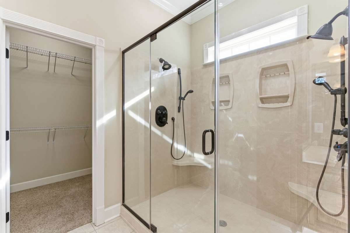 Luxurious primary bath featuring an extended double vanity with rich wood cabinetry, relaxing soaking tub, and large walk-in shower, all leading to an expansive walk-in closet for effortless organization.