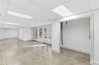 Space to possibly add downstairs laundry closet, Expansive open area in the finished basement with polished concrete floors, neutral palette, and double doors to the backyard, offering a versatile space for a game room, gym, or large gatherings.