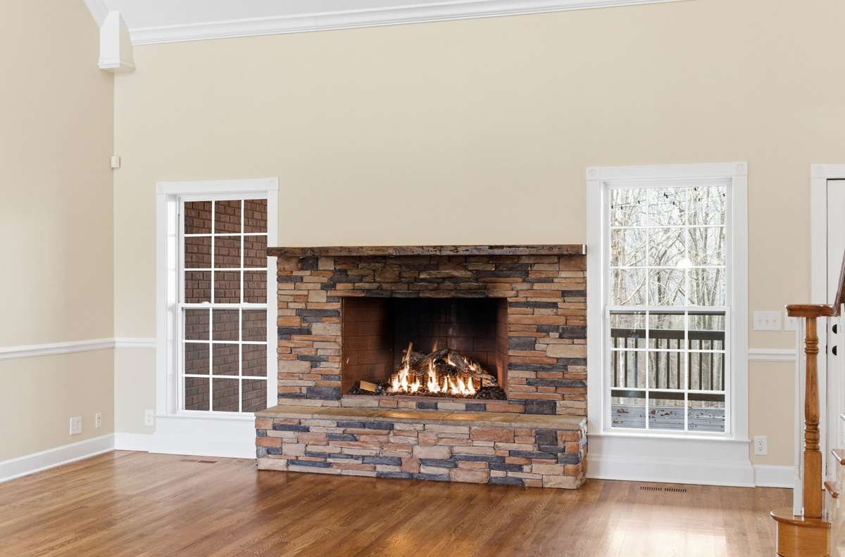 Main floor family/living room features a stacked-stone fireplace, soaring vaulted ceilings, and hardwood floors, with easy walkout access to the covered deck that is perfect for grilling, relaxing, and entertaining.