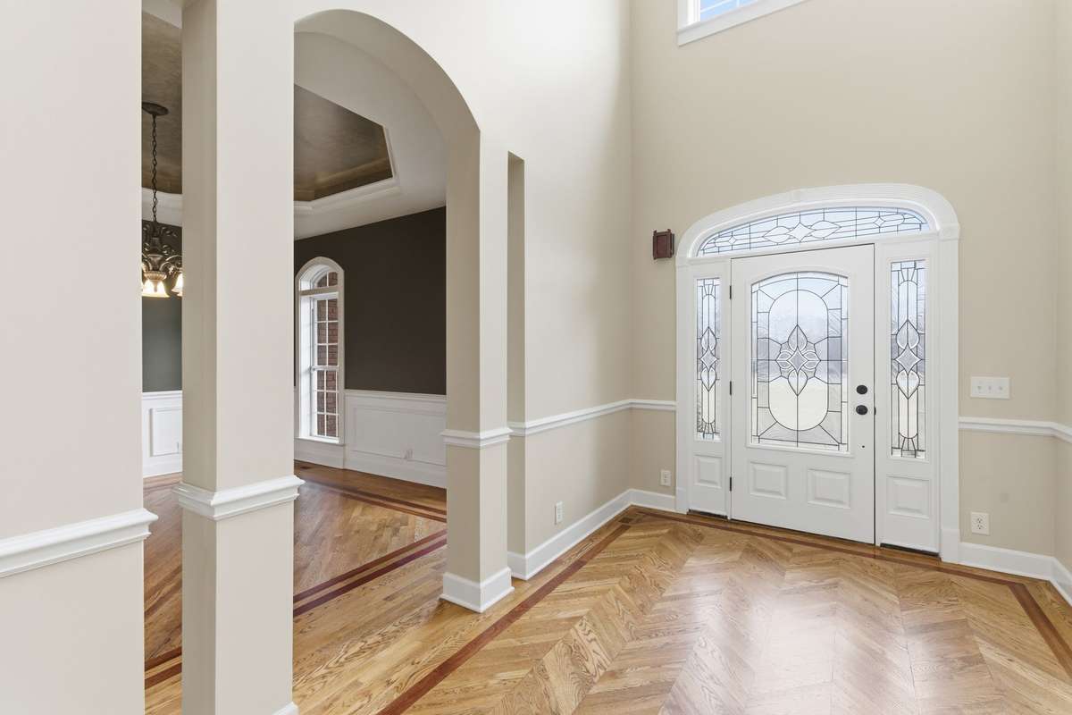 Grand foyer with soaring ceilings, custom inlaid hardwood floors, and graceful arched openings that provide a stunning first impression as you step inside.