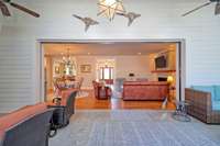 View with sliding wall/glass doors open to covered screened porch and stone patio area .