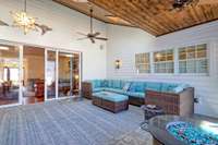 Cedar plank ceiling adds warmth to this outdoor living space. Note the pretty chandelier and wall sconces.