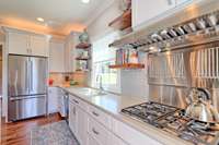 WOLF gas cooktop, with warming lamps and warming racks. Stainless appliances throughout kitchen. Under cabinet lighting with under counter electrical outlets.