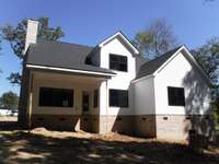 Your home from the rear. There will be a deck under the covering at the back door. Lots of shade trees casting shade on this wooded lot.