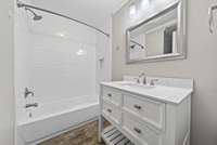 Tiled bathroom floor, white vanity with quartz countertop add craftsman style to the bathroom.