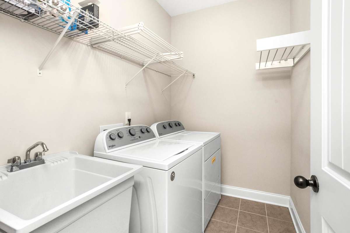 The laundry room featuring a sink and storage is located near the kitchen.