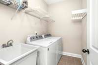 The laundry room featuring a sink and storage is located near the kitchen.