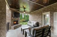 Large back porch  w/ fireplace, strung lights, a TV, and ample space for seating- perfect for hosting and enjoying outdoor living