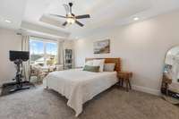 Large primary bedroom featuring tray ceilings, walk-in closet and ensuite bath