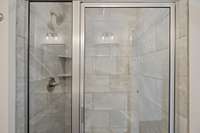 Large tile shower featured in the primary bathroom