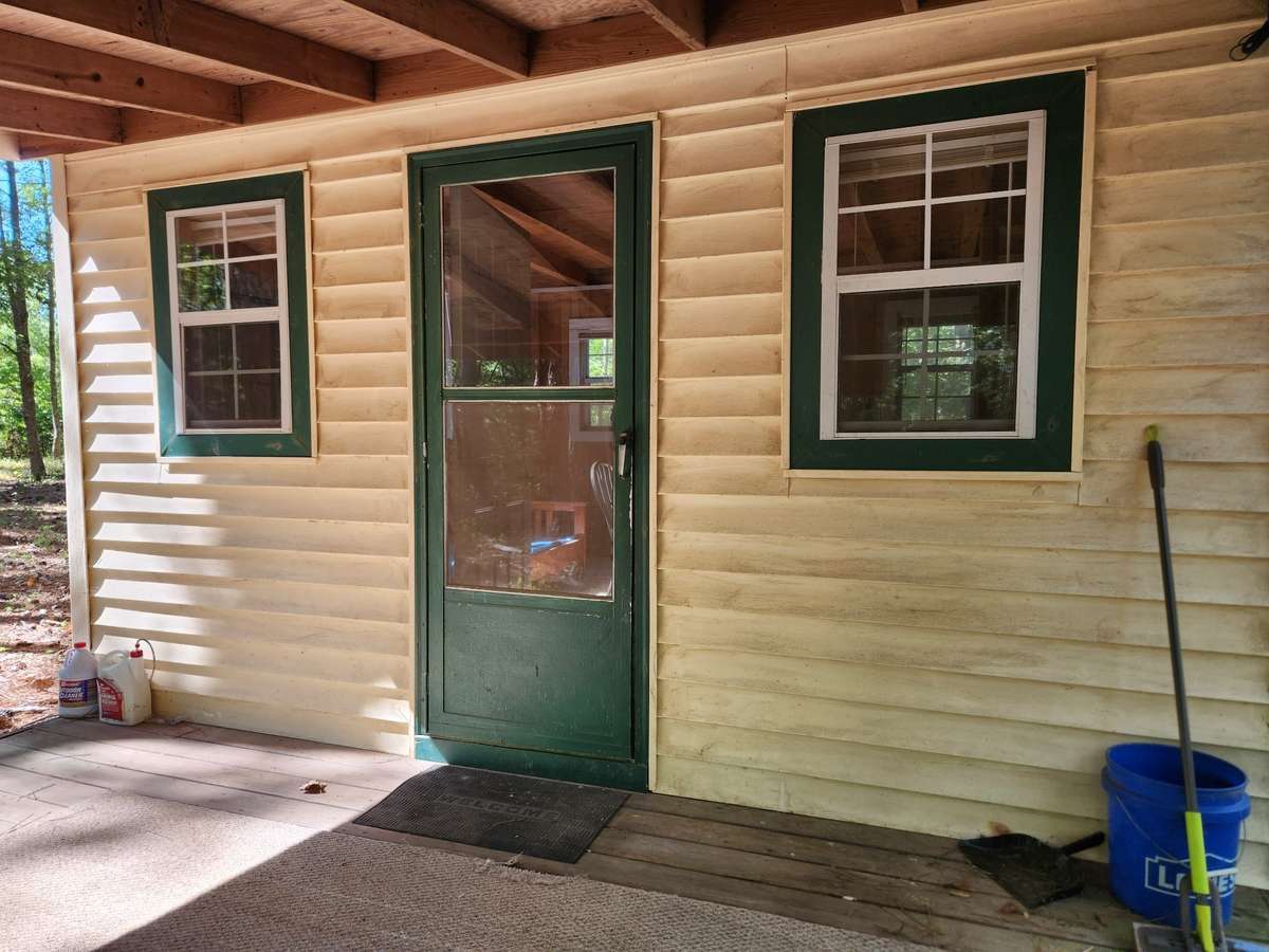 Hunting cabin has bright natural light in the daytime with five windows downstairs, three windows upstairs, and storm doors at the front and back doors.