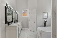 Elegant primary bathroom featuring dual vanities, a luxurious soaking tub, and a spacious layout designed for comfort and convenience.