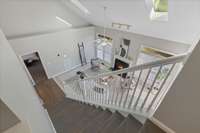 Stunning bird’s-eye view from the top of the stairs overlooking the open-concept living room, showcasing soaring ceilings, elegant finishes, and abundant natural light.