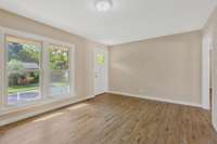 Bright and welcoming living room with new laminate flooring, nice neutral paint, light fixture and front door.