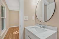 Primary half bath with new vanity, sink, faucet, mirror and vanity light.