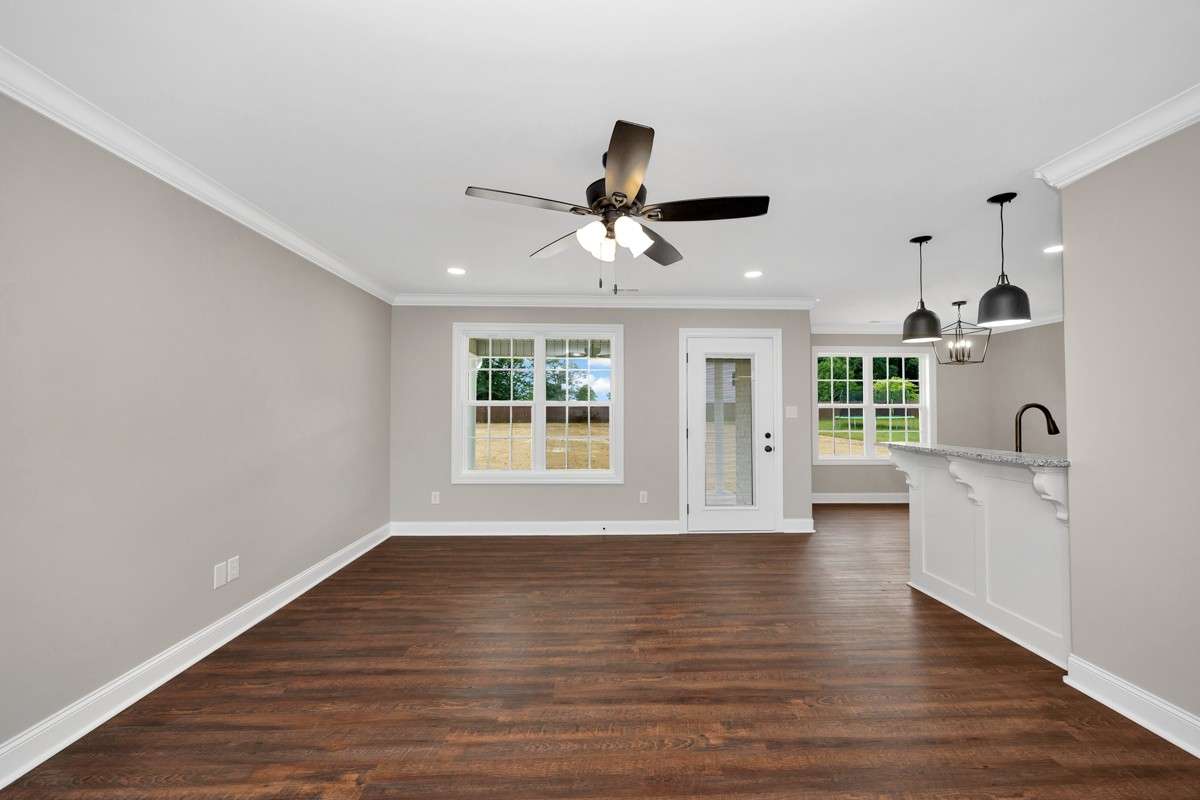 Living Room- LVP flooring, ceiling fan, crown molding, recessed lighting