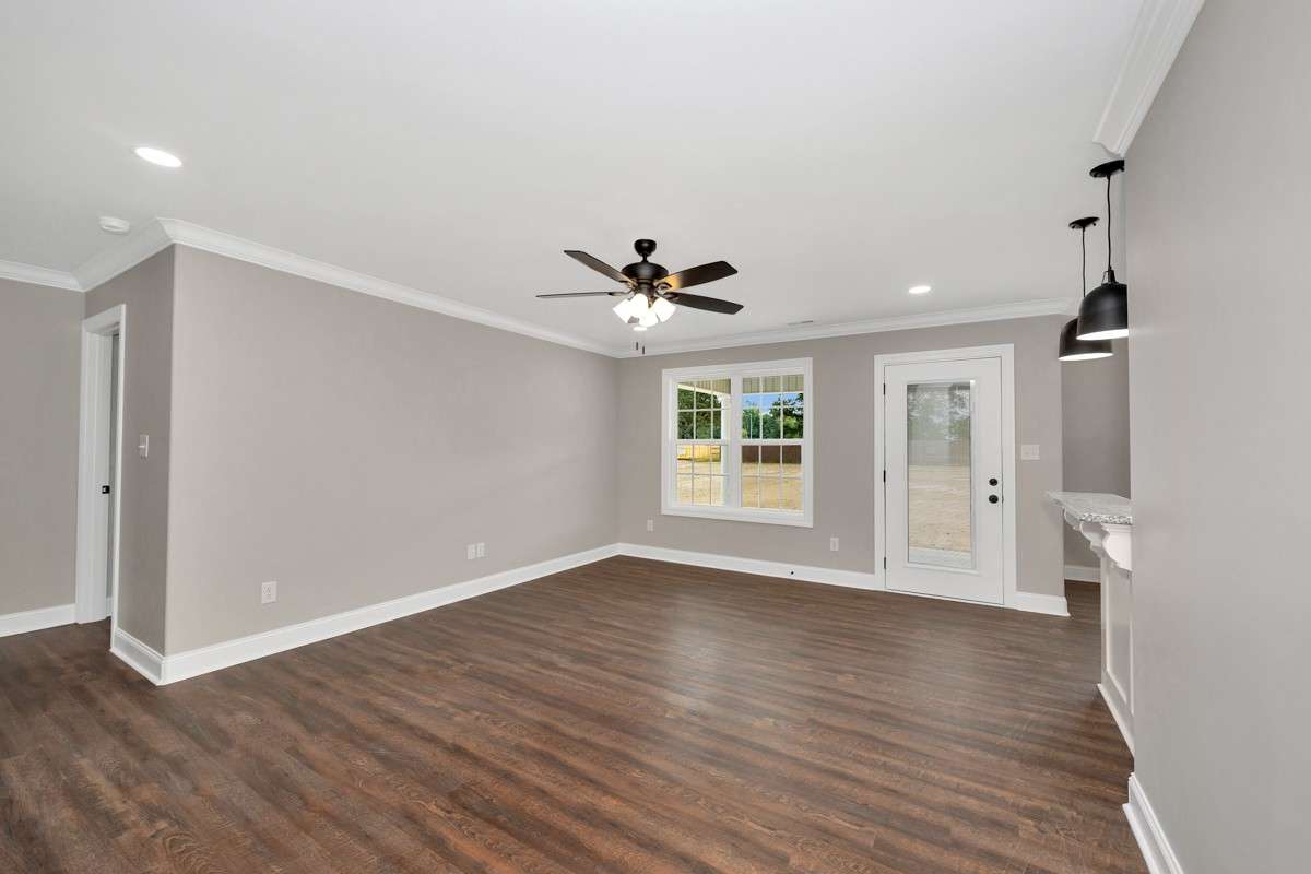 Living Room- LVP flooring, ceiling fan, crown molding, recessed lighting