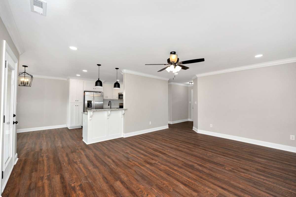 Living Room- LVP flooring, ceiling fan, crown molding, recessed lighting