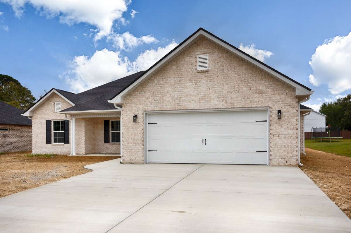 Full brick, two-car attached garage, concrete driveway and sidewalk, covered front porch with home entry