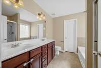 Primary Bathroom has a double bowl vanity with row of drawers, separate tub and shower and door leading to the large walk-in closet