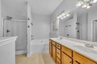 Separate shower and tub with dual vanities finished in cultured marble with integrated sinks.