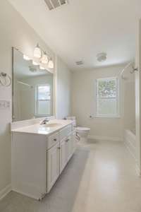 Long, spacious bathroom that has a wide doorframe and floors - also has a tub/shower combo