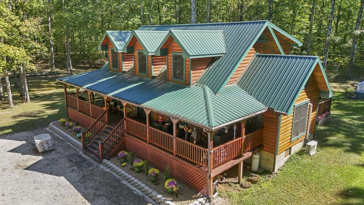 An elevated view highlighting the home’s thoughtful design, covered front porch, and natural woodland surroundings that provide privacy without isolation.