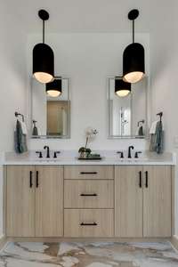 The space also features double vanities with sleek quartz countertops, ample storage, and custom lighting that adds warmth and sophistication. Stylish mirrors, modern hardware, and high-end finishes complete the look.