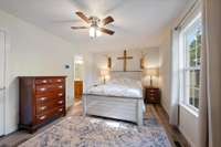 The Primary Suite sits on the left side of the home &  features a walk-in closet, ceiling fan, large window overlooking the front yard, and en-suite bathroom.