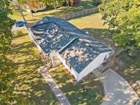 Aerial view of homes concrete parking pad and entire home. Side fence line show side of property, but back of property goes past beyond of the end of the fence line.