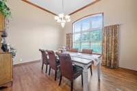 Soaring ceilings in this formal dining room, and a beautiful window allows for natural sunlight to beam through