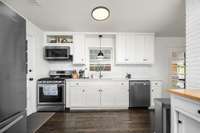 Updated kitchen with white cabinetry, subway tile backsplash, and stainless steel appliances