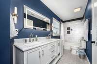 Primary ensuite bathroom has been thoughtfully updated with double vanity, marble countertop, and a tiled shower-tub combo