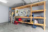 Attached 2 car garage featuring custom workbench stays with the home — stay perfectly organized with plenty of space to park your cars and have storage space.