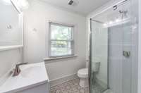 Continue on down the hall to the primary suite. First you'll find the primary bathroom, and outside the bathroom, you'll find built-in shelves for toiletries and linens, as well as a door to close off the primary suite area!