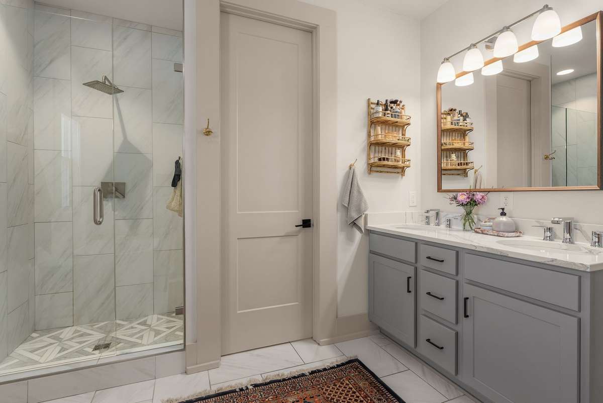 A spacious glass-enclosed shower and dual vanity combine clean lines with everyday functionality—bringing elevated design to daily routines.