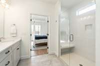 The bathroom includes a 6-foot glass-enclosed shower with a tiled bench seat and quartz countertops. The shower has an upgraded handheld shower head.