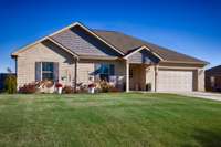 Front of house - Full brick, concrete driveway, covered front porch, gutters, classic landscaping, 2-car garage with single rollup door front facing