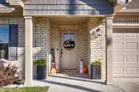 Front of house - Full brick, concrete driveway, covered front porch, gutters, classic landscaping, 2-car garage with single rollup door front facing