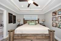 Primary Bedroom- LVP flooring, crown molding, trey ceiling, recessed lighting, ceiling fan, walk-in closet, en-suite bath