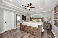 Primary Bedroom- LVP flooring, crown molding, trey ceiling, recessed lighting, ceiling fan, walk-in closet, en-suite bath