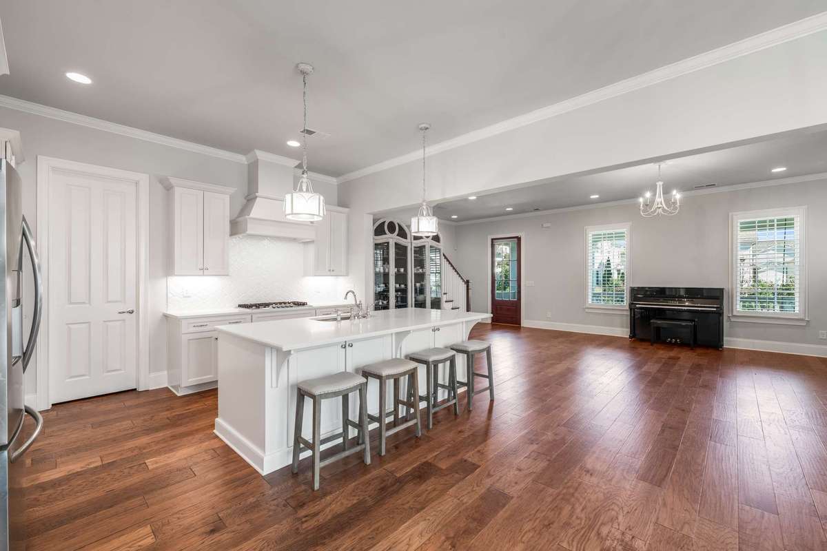 The main floor open living plan offers hardwood flooring, neutral color pallets, large windows, and ample overhead recessed lighting.